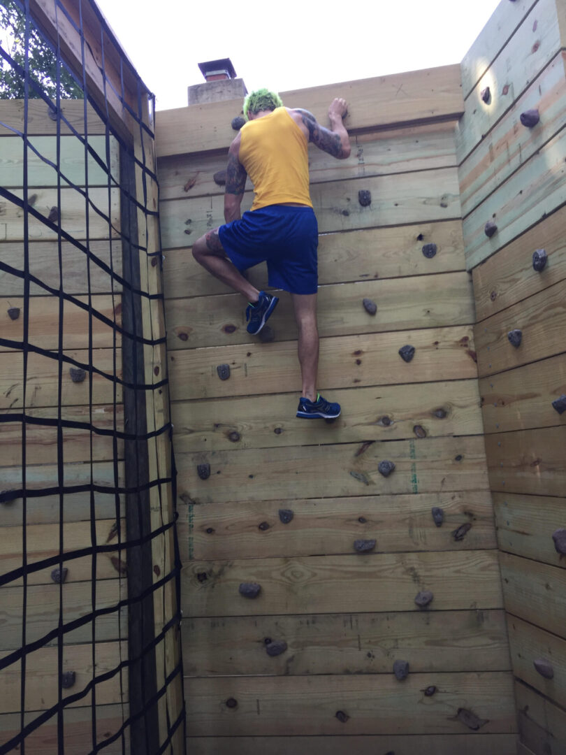 A person wearing a yellow color tank and climbing up
